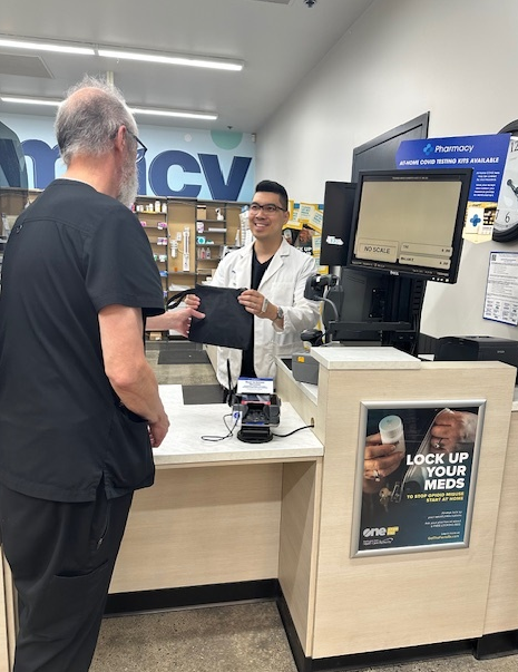 Pharmacist handing a lock bag to a patient.