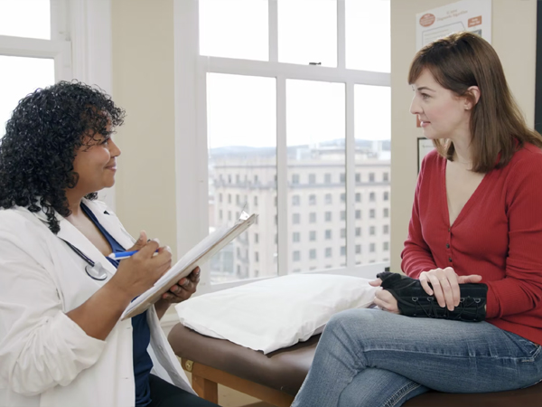 A doctor with a clipboard and a patient sitting down.