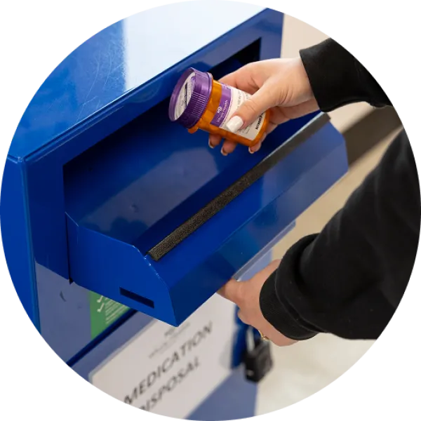 Someone using a dropbox to safely dispose of medications.